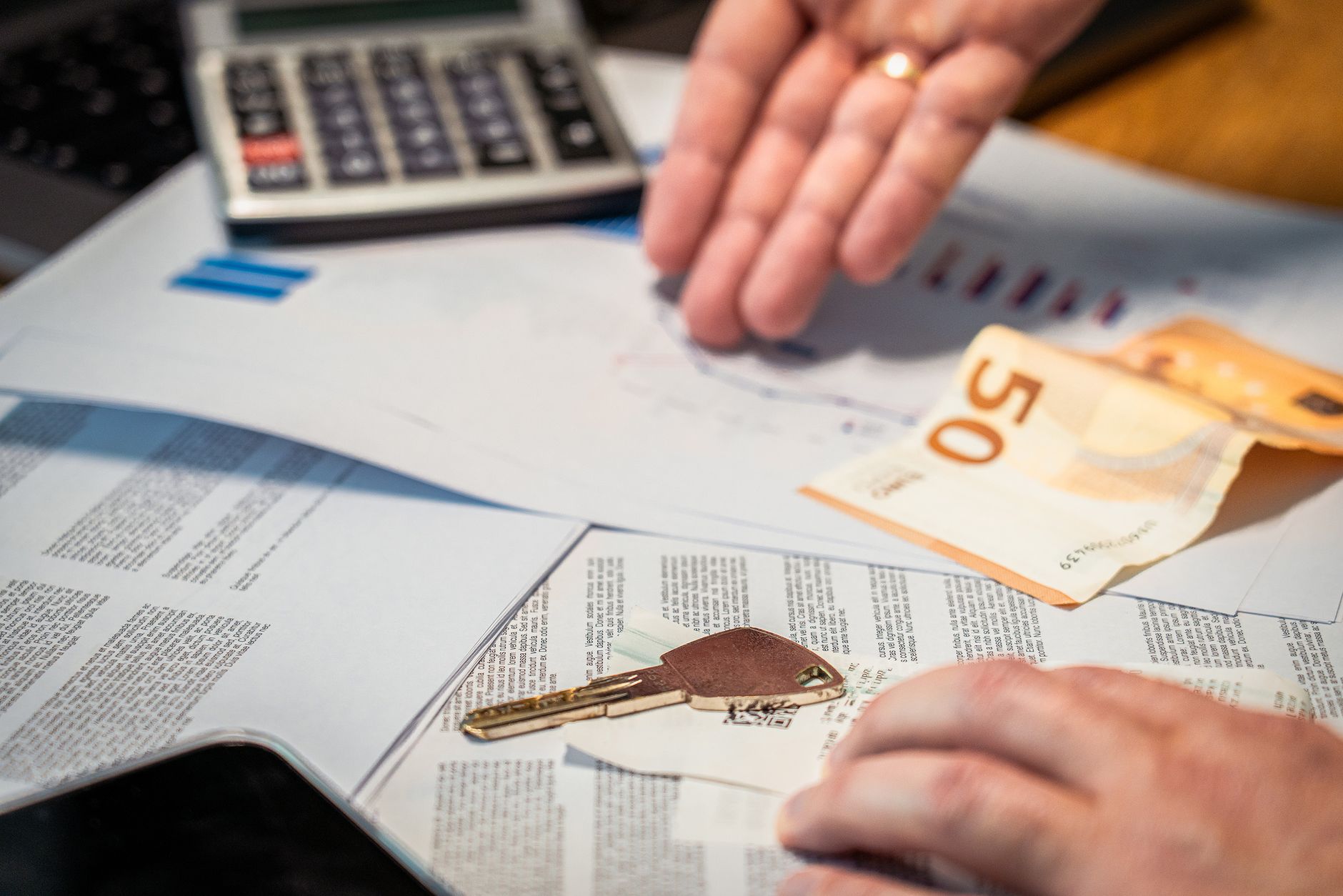 Mão contando notas ao lado de uma calculadora